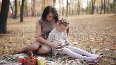 年轻漂亮的妈妈和女儿在秋天公园的<strong>粉笔</strong>板上用<strong>粉笔写字</strong>